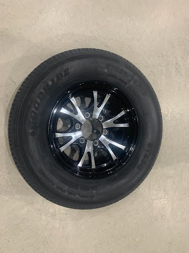 Black lip aluminum wheel with a ST225/75 15-inch radial tire by Tex Trail mounted on a vehicle.