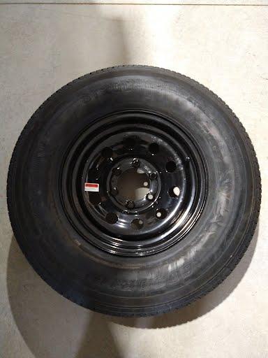 Black 235/80R16 tires mounted on PJ Trailers MFG Inc. 6-lug wheels with 6x5.5 bolt pattern, showcasing rugged wheel and tire setup.