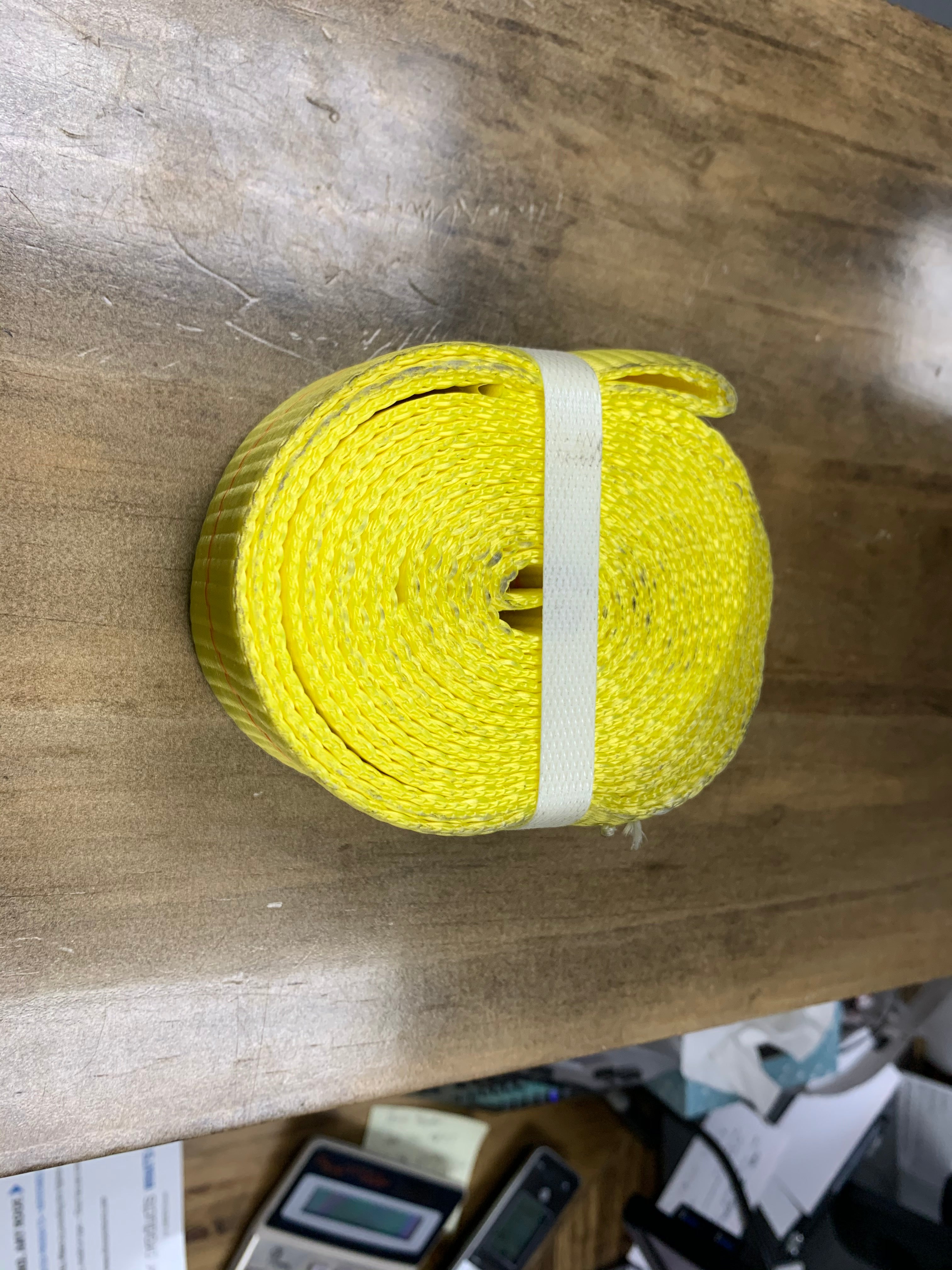 Yellow Tex Trail wheel strap cargo control lasso securing items on a vehicle or trailer for safe transport.
