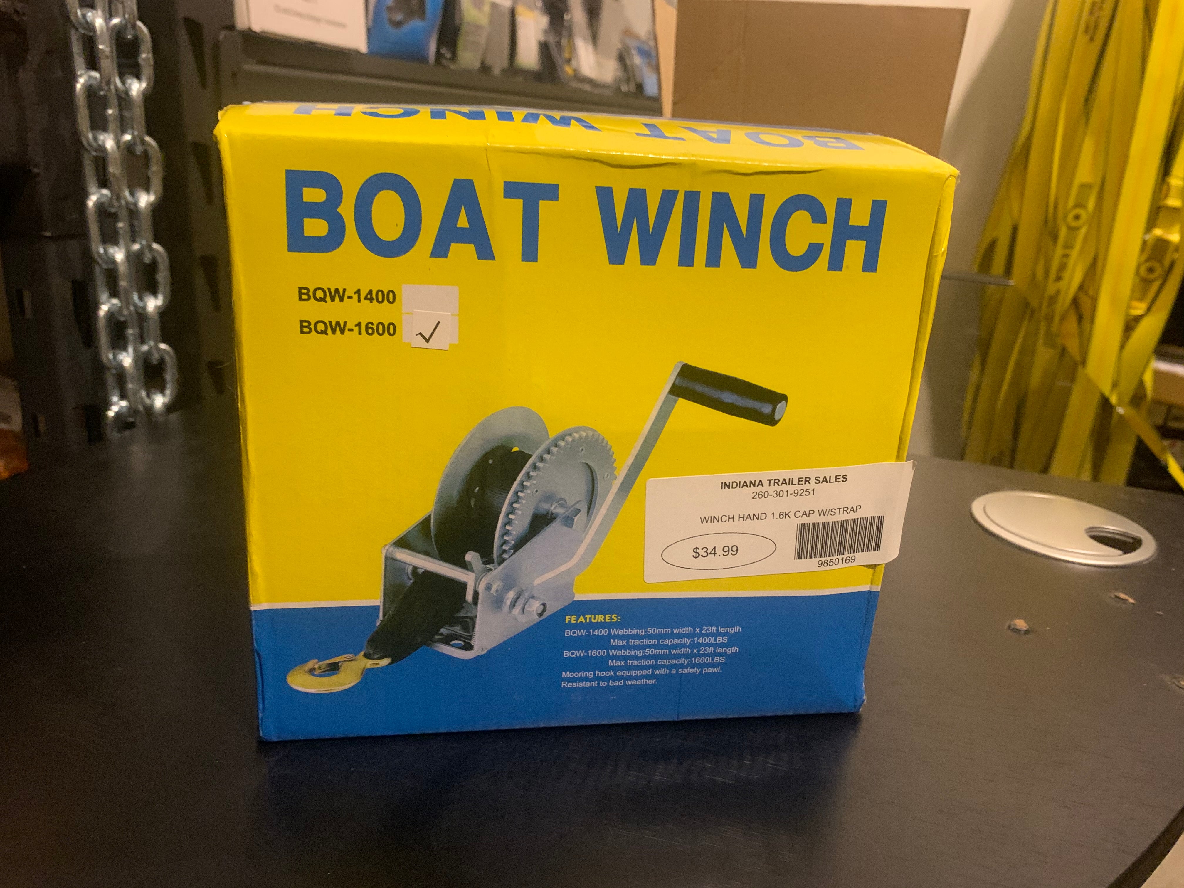 Tex Trail hand winch with 1.6K capacity and strap for cargo control, shown with durable handle and strap in a storage setting.